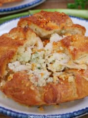 A round white plate with blue trim with a round store-bought croissant on it filled with a savory rotisserie chicken mixture.