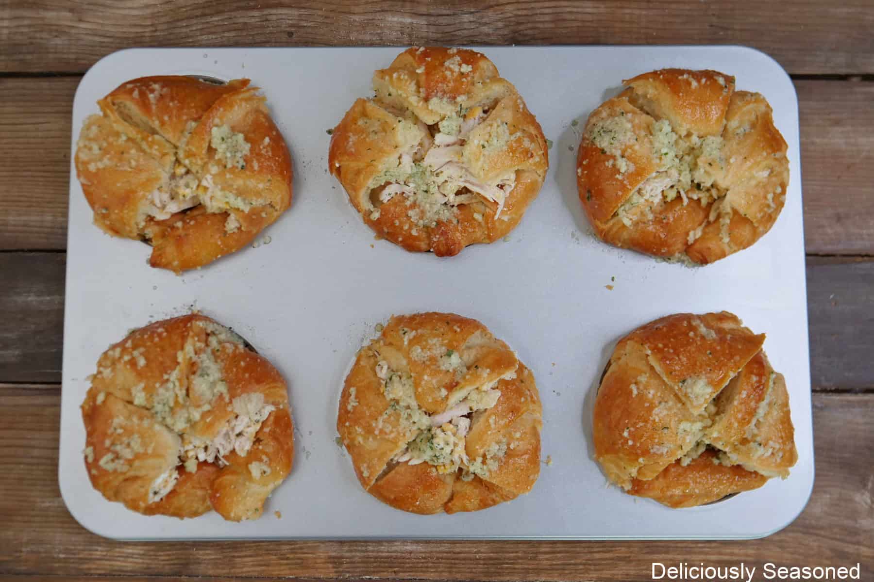 A silver baking sheet with six chicken ranch crusted croissants in it.