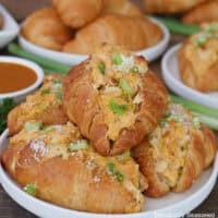 A round white plate with four mini buffalo chicken croissants placed on it.