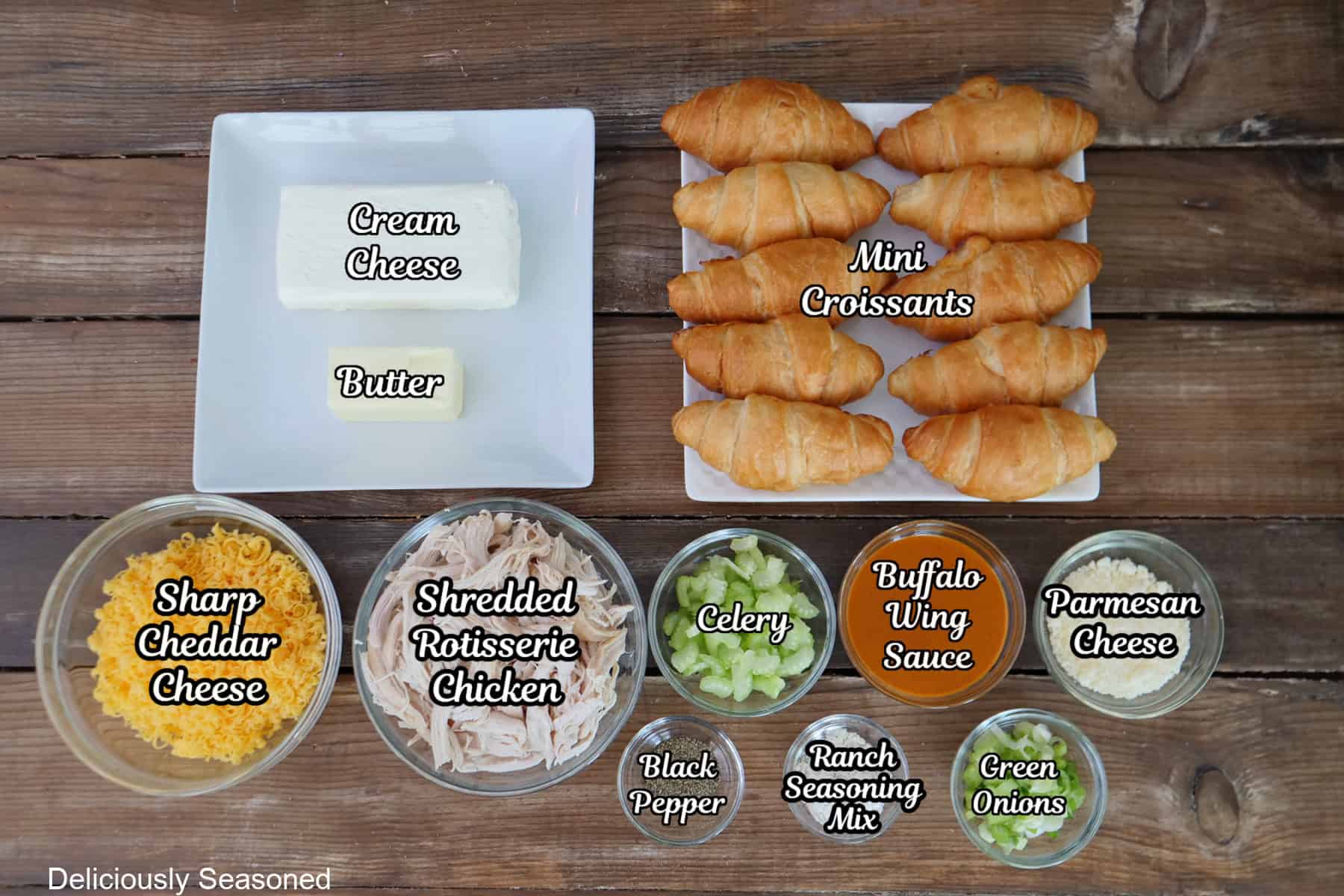 A rustic wood surface with all the ingredients placed on it to make mini buffalo chicken croissants.