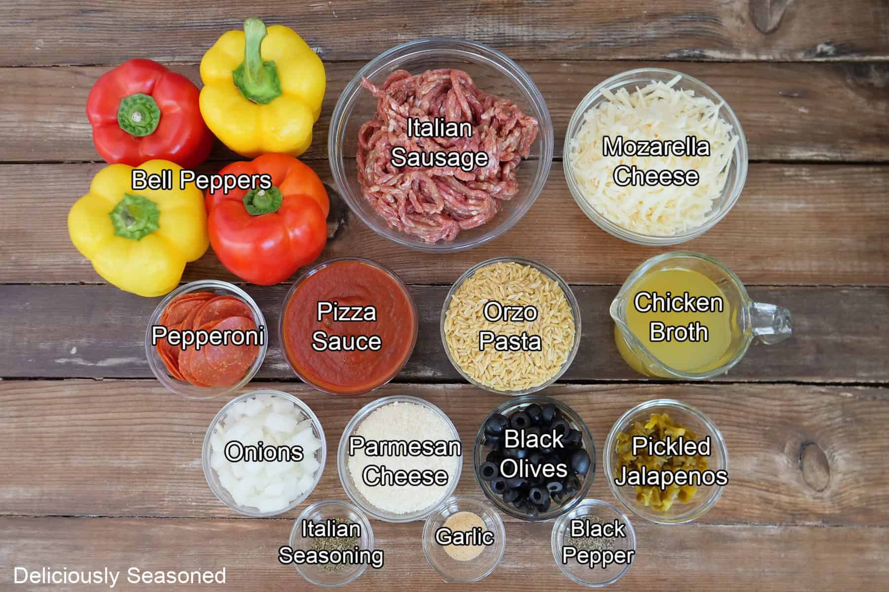 A rustic wood surface with all the ingredients placed on it to make pepperoni pizza stuffed peppers.