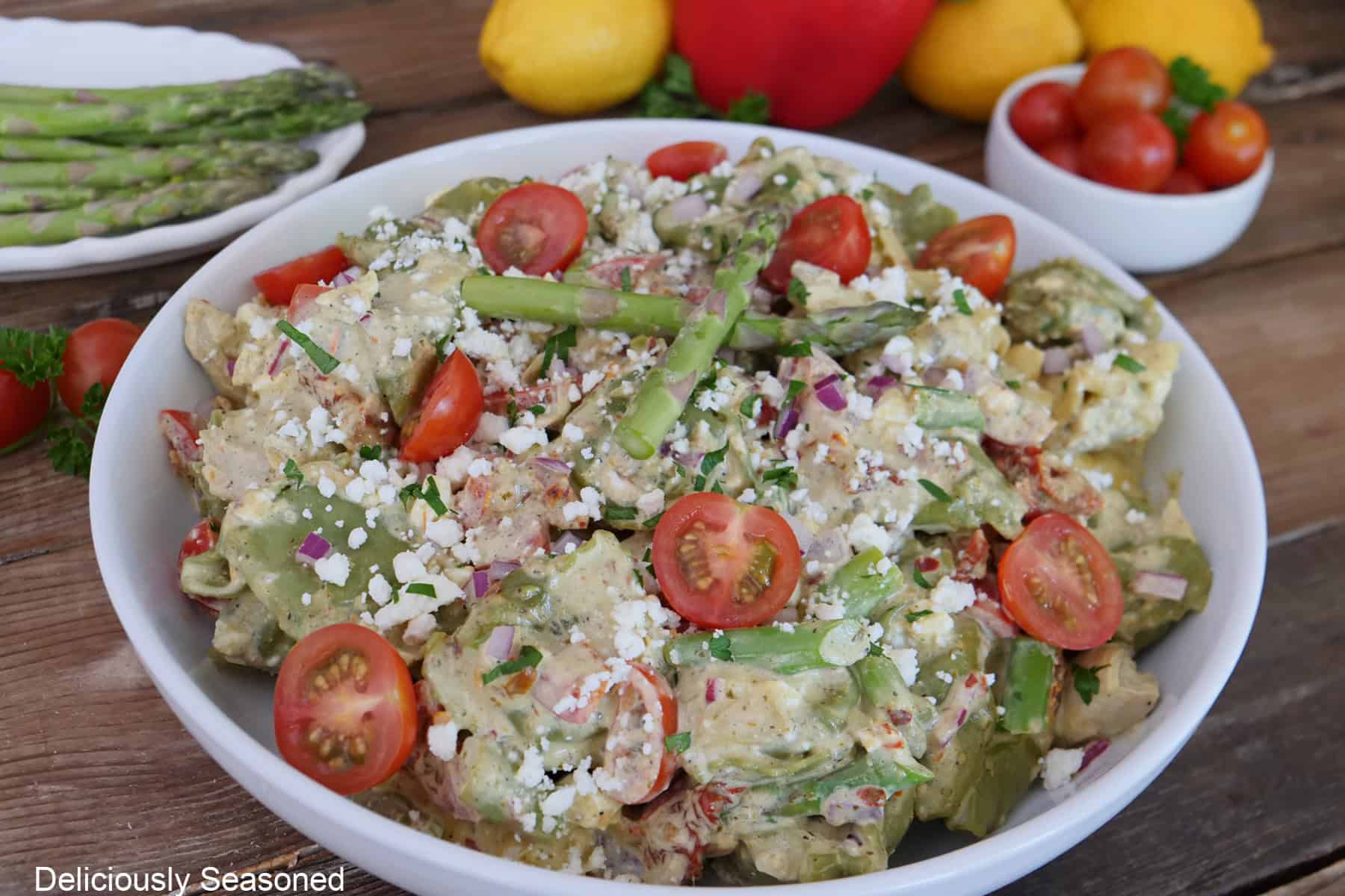 A white bowl filled with tortellini pasta salad placed on a rustic wood surface.
