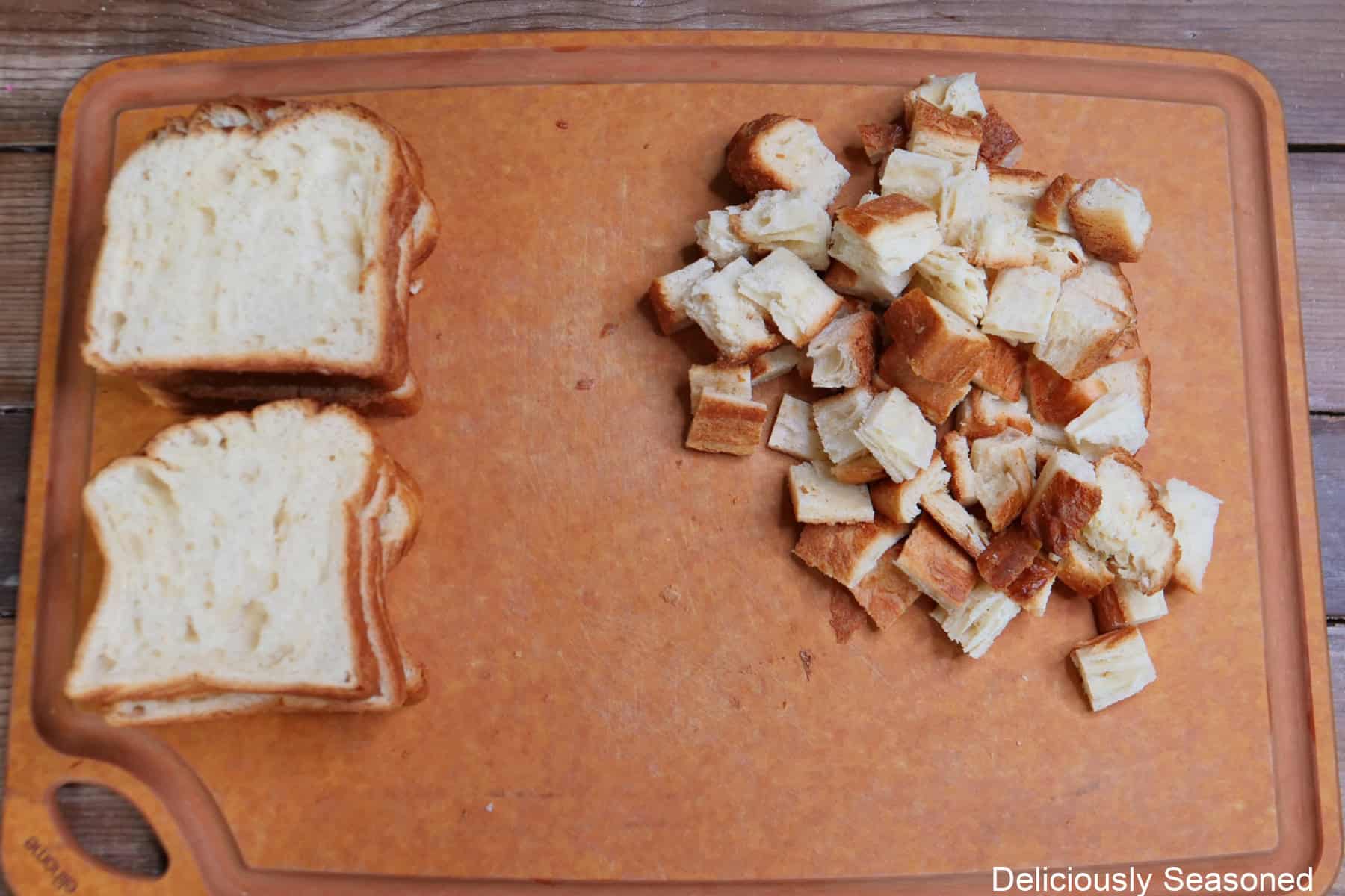 A wood cutting board with croissant bread and croissant bread that has been cut into ½ inch pieces.