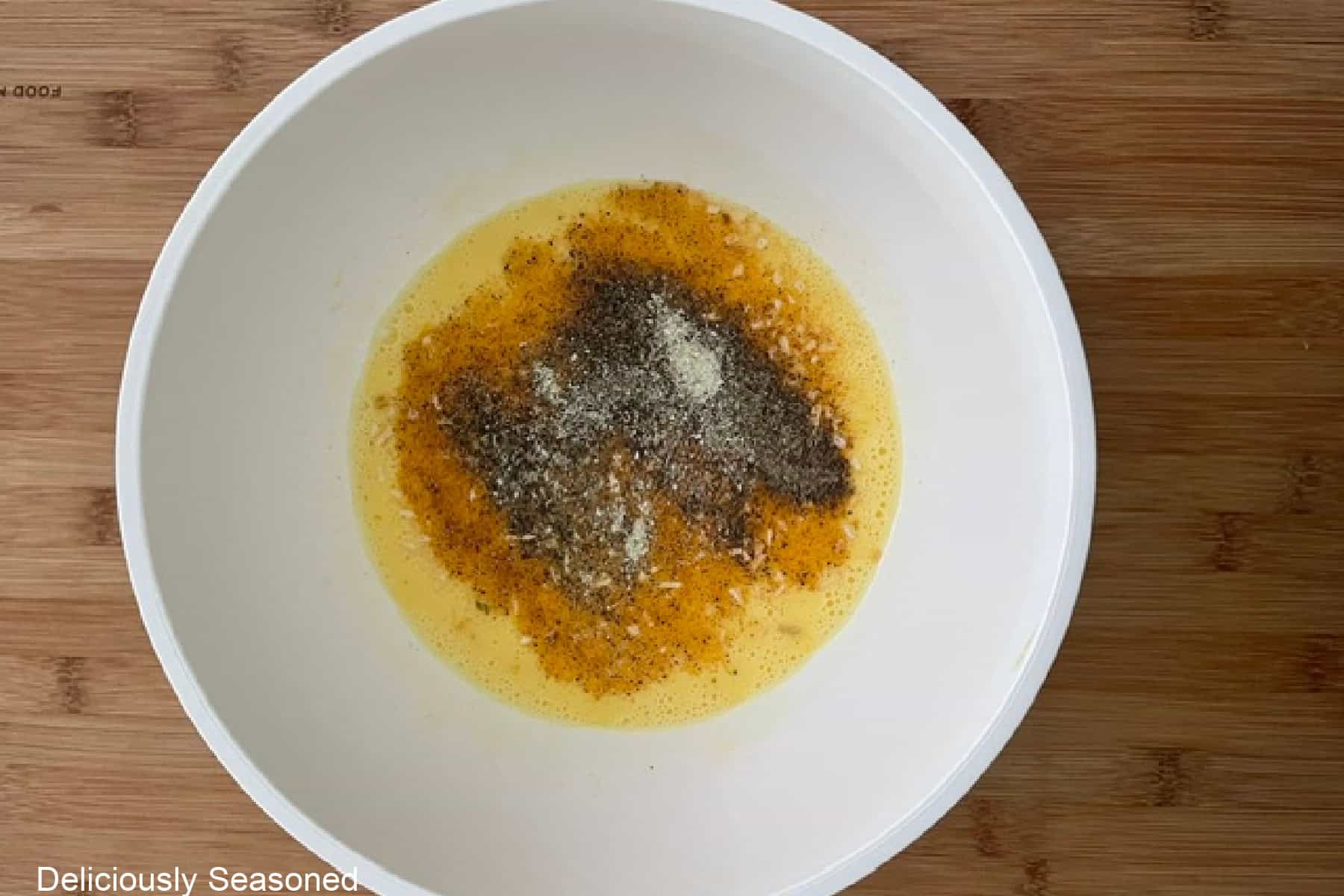 A white bowl filled with eggs and seasonings before being whisked together.