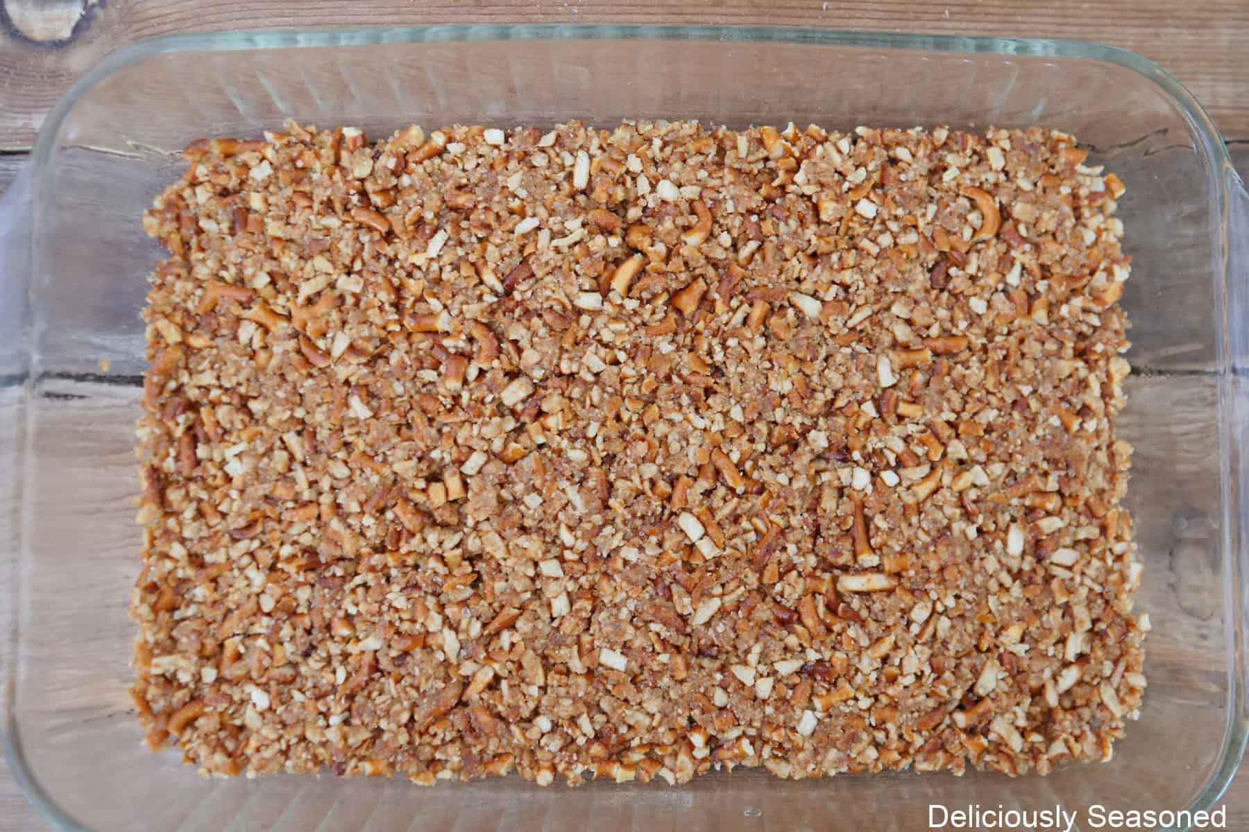 A glass 9 by 13 baking dish with a pretzel crust in it.
