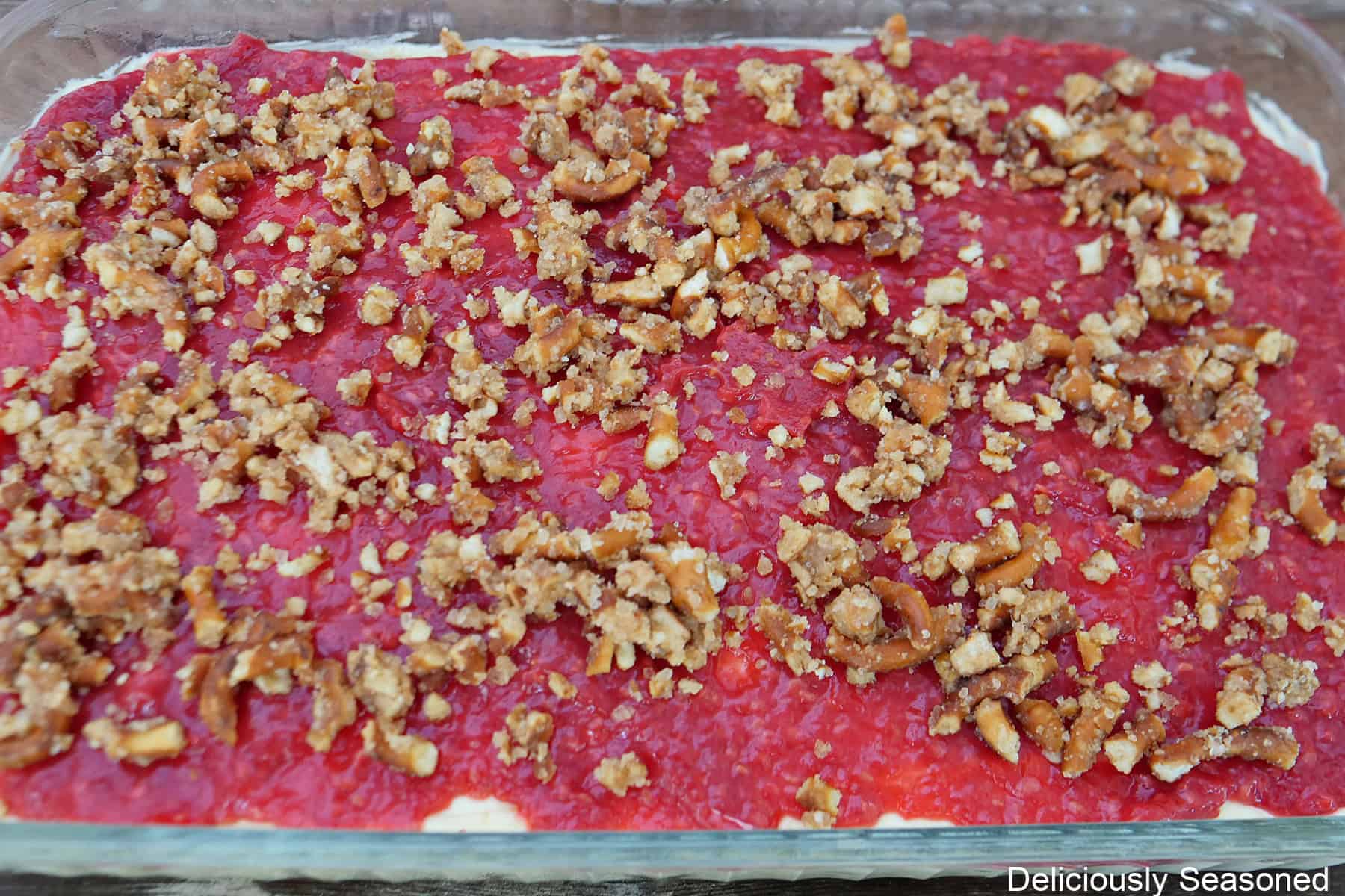 A glass 9 by 13 baking dish with a lemon raspberry pretzel salad in it before being cut and served.