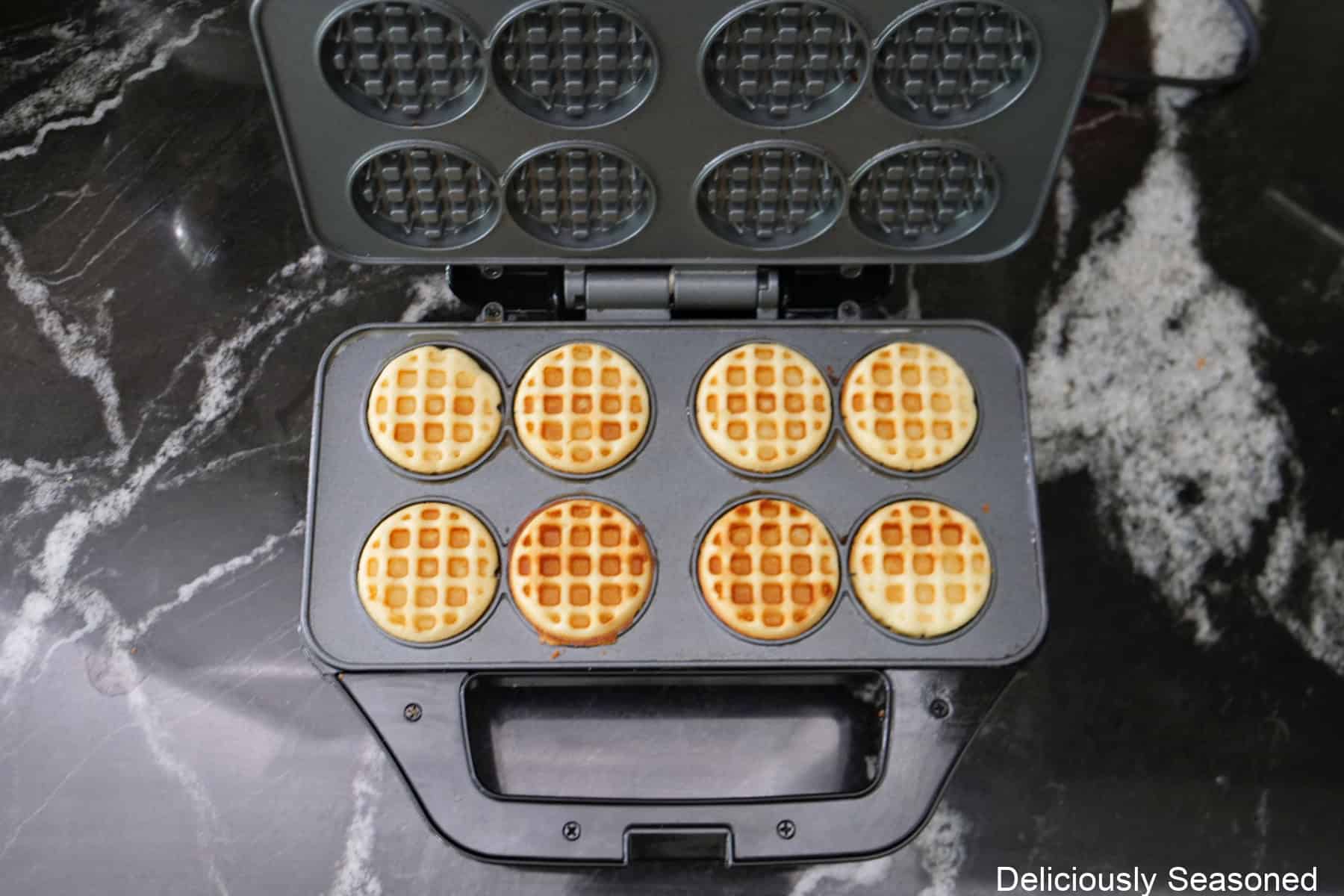 A mini waffle maker with eight cooked mini waffles in it.