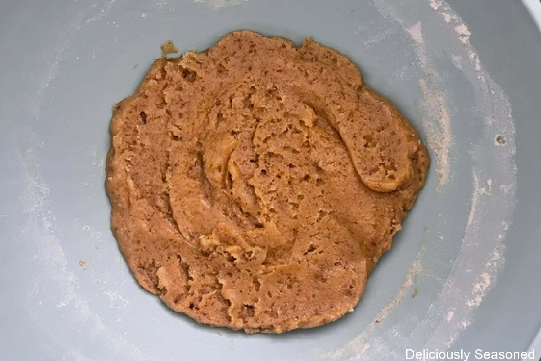 A light colored mixing bowl with the snickerdoodle cookie batter in it.