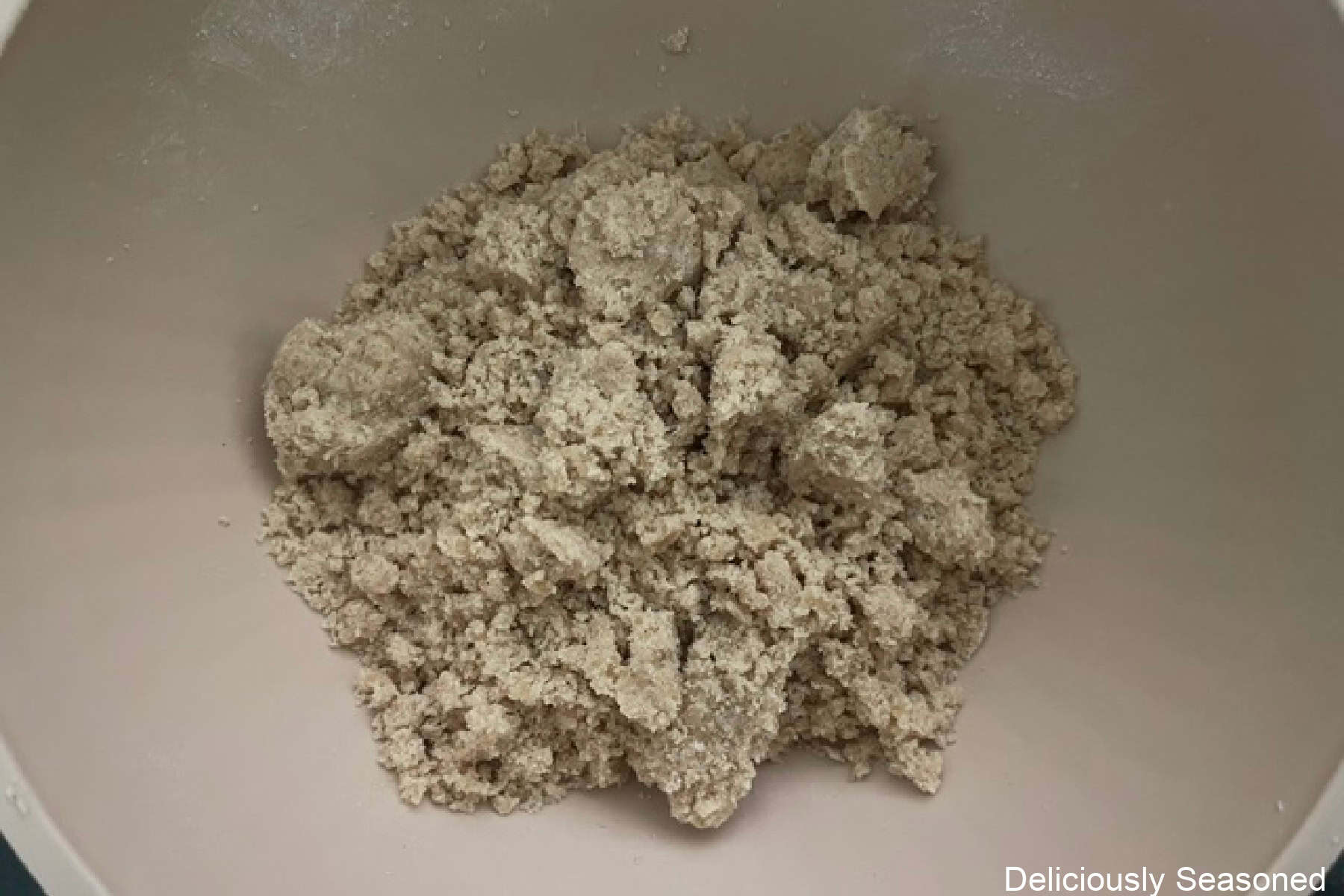 A light colored bowl with a mixed crumb topping in it.