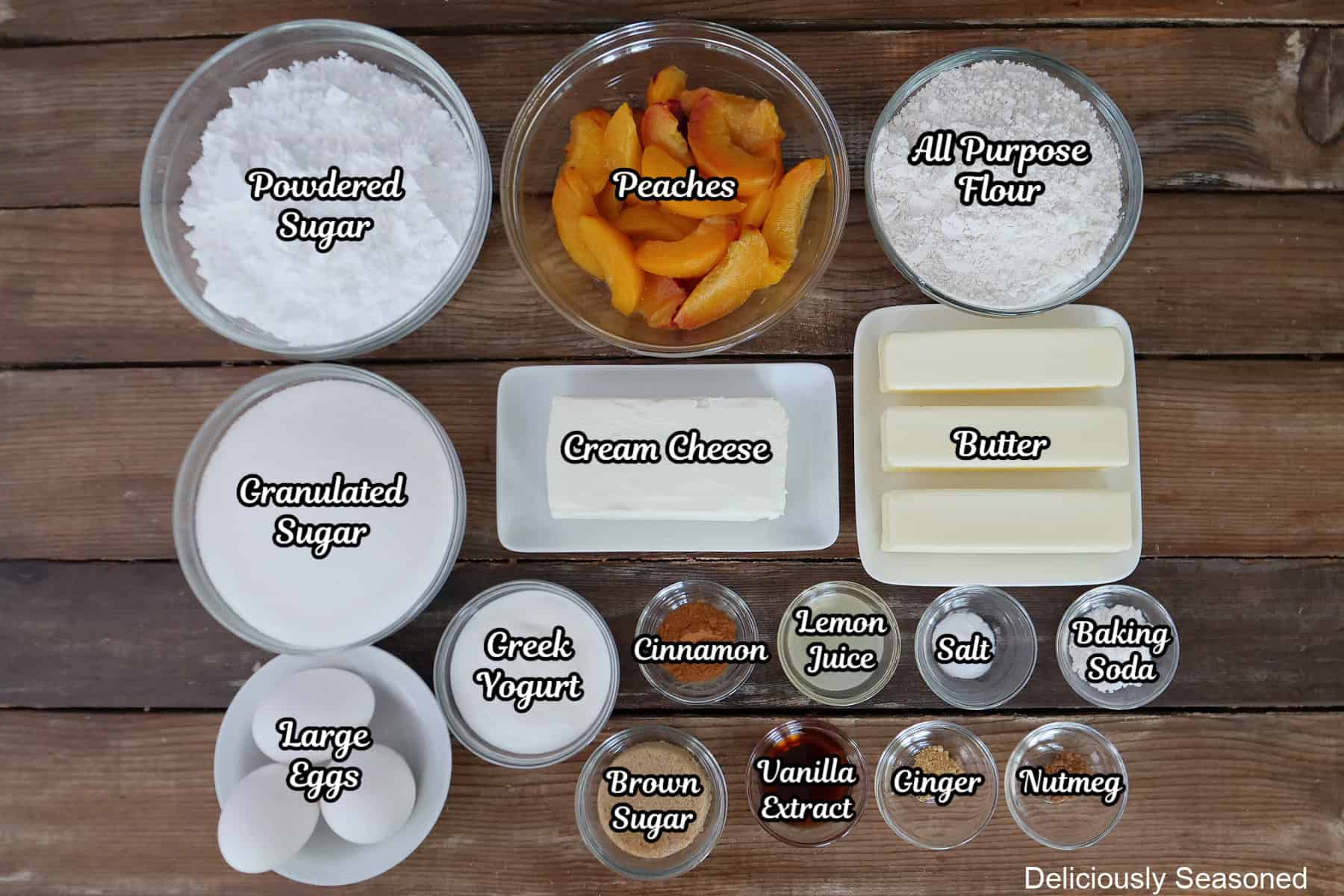 A rustic wood surface with all the ingredients placed on it to make peach cobbler cupcakes with brown butter frosting.