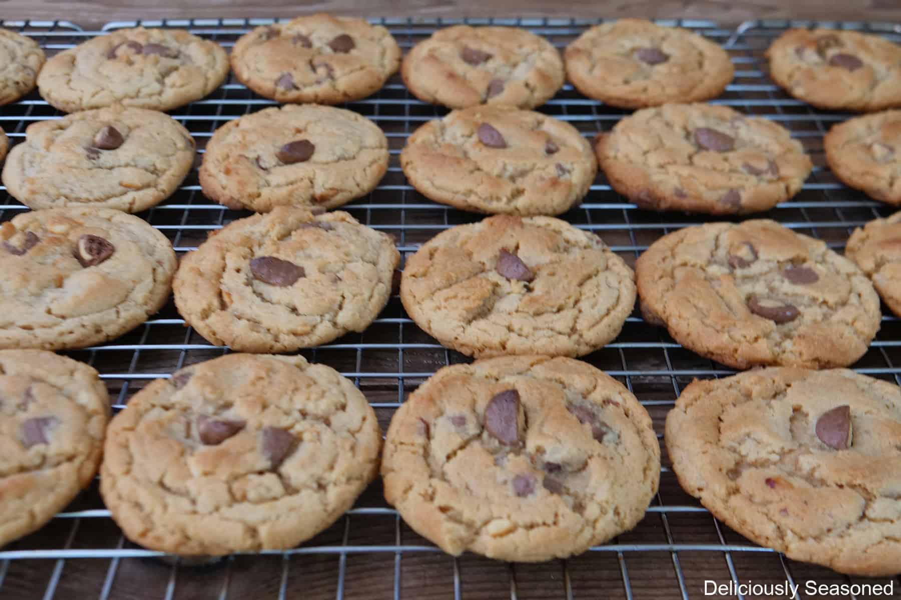 A wire rack with two dozen peanut butter cup cookies on it after being baked.