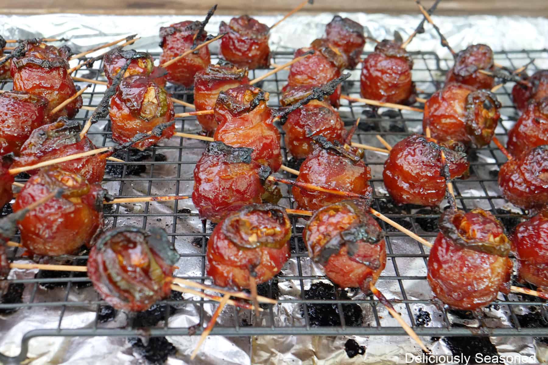 Smoked bacon wrapped meatballs on a foil lined baking sheet with a wire rack on top after they have been smoked to crispy perfection.