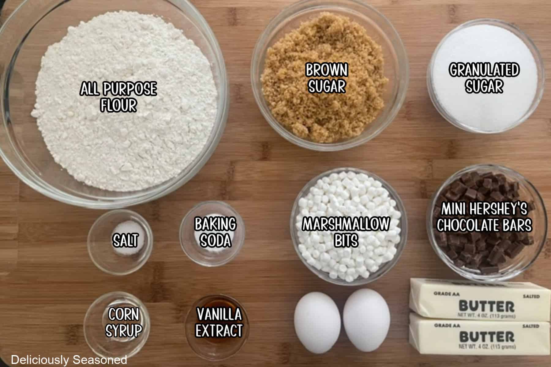 A wood surface with all the ingredients needed to make S'mores cookies placed on it.