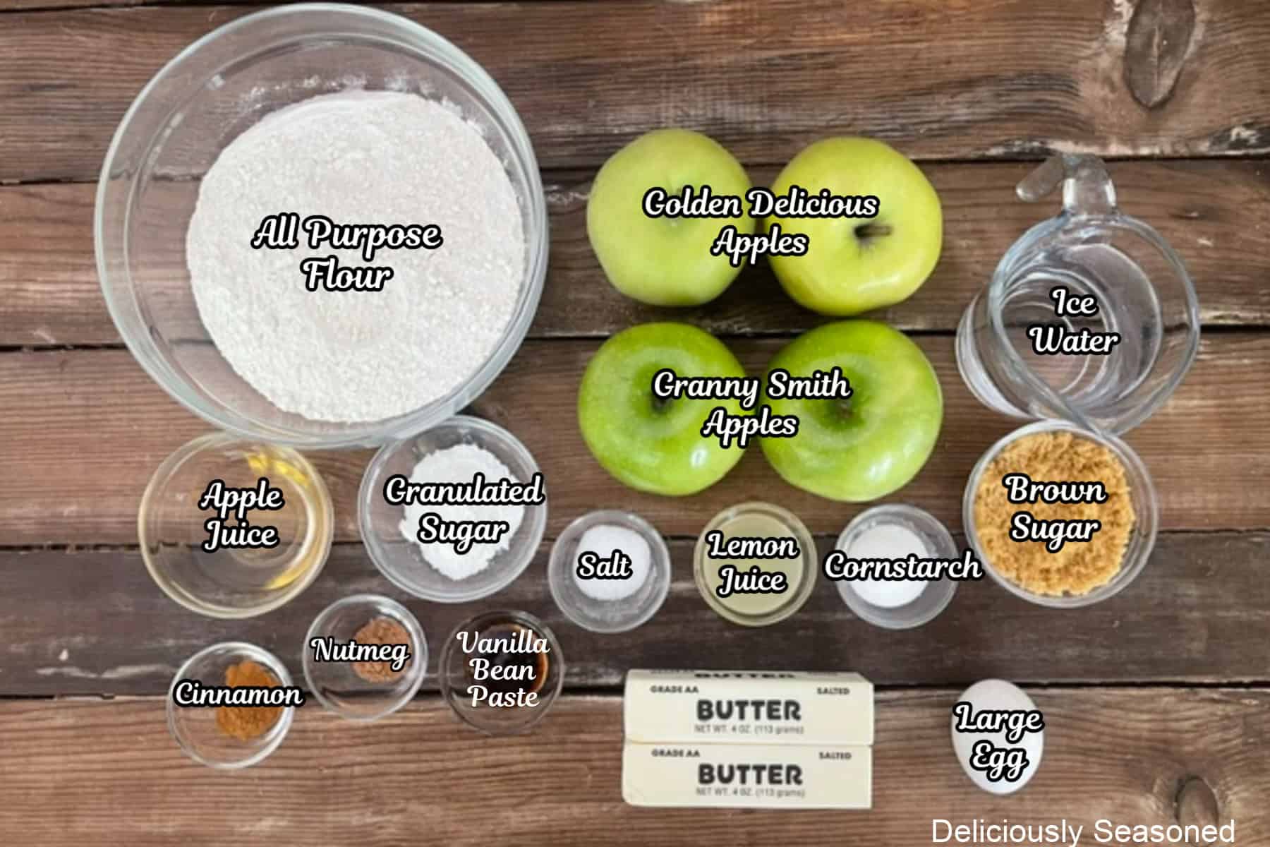 A wood surface with all the ingredients placed on it to make apple pie bars.