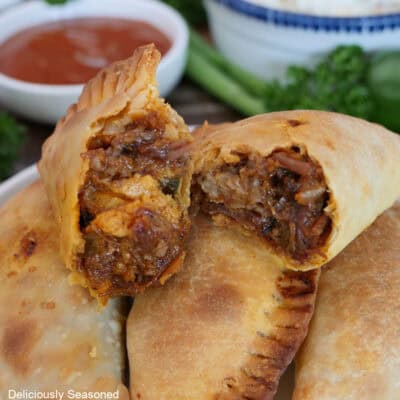 Five beef brisket empanadas stacked on each other with the two on top with bites taken out of them.