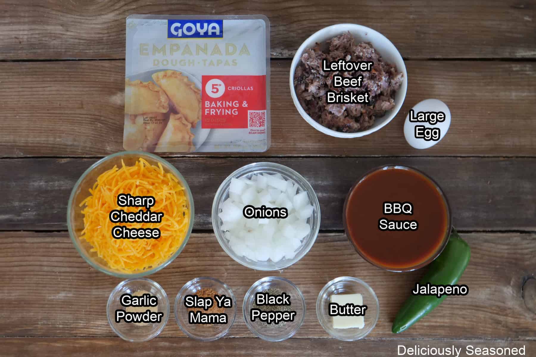 A wood surface with all the ingredients placed on it to make beef brisket empanadas.