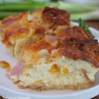 A serving of cheesy ham bread pudding on a white plate