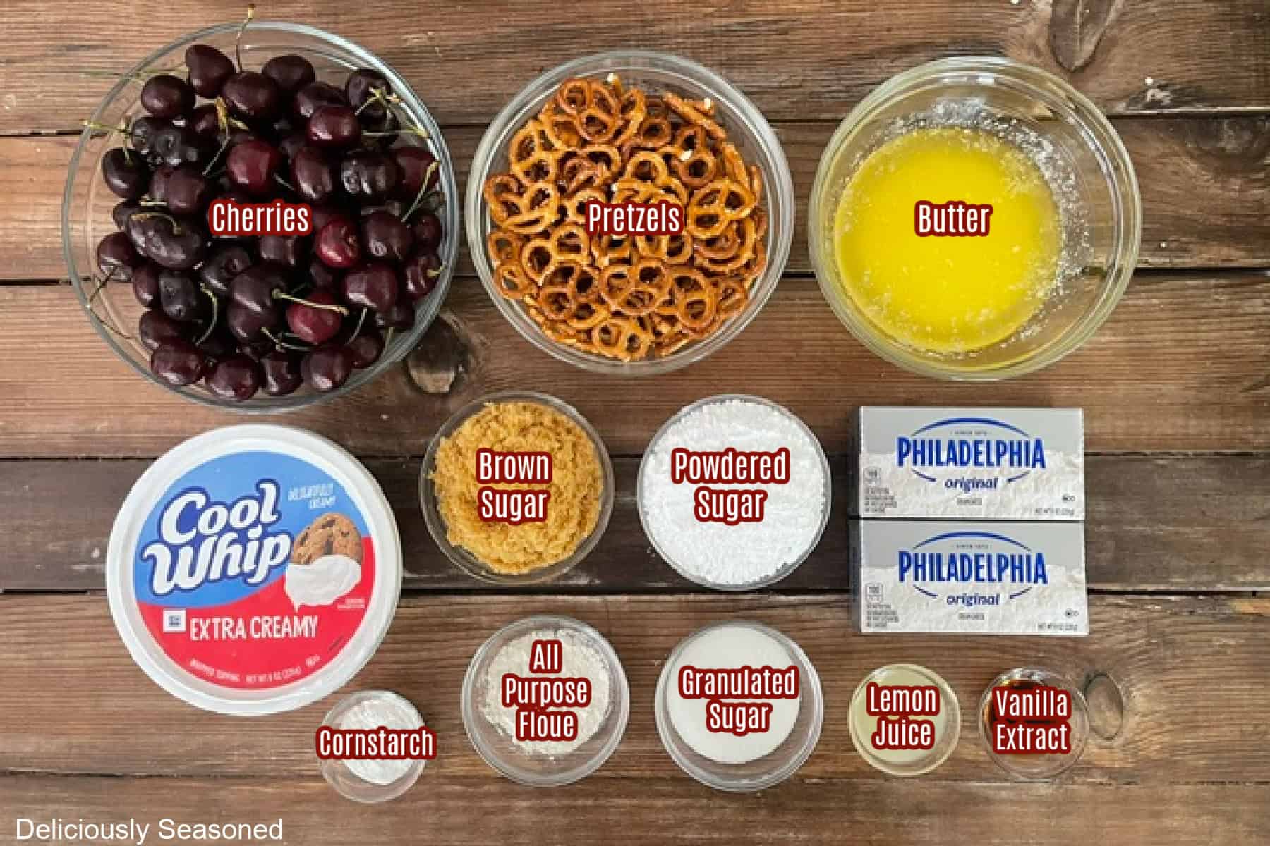 A wood surface with all the ingredients placed on it to make cherry pretzel salad.