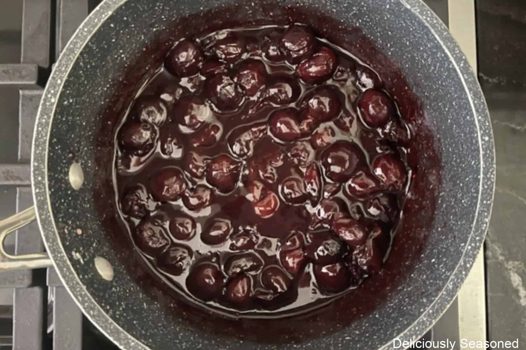 A saucepan with homemade cherry filling cooking on the stove.