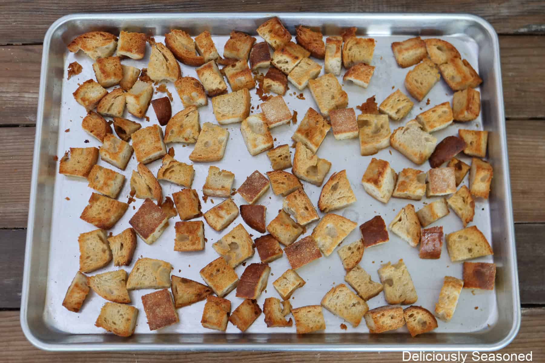 A baking sheet with toasted cubes of Italian bread on it.
