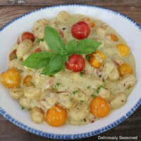 A blue trimmed white bowl filled with a serving of tomato pesto alfredo gnocchi.