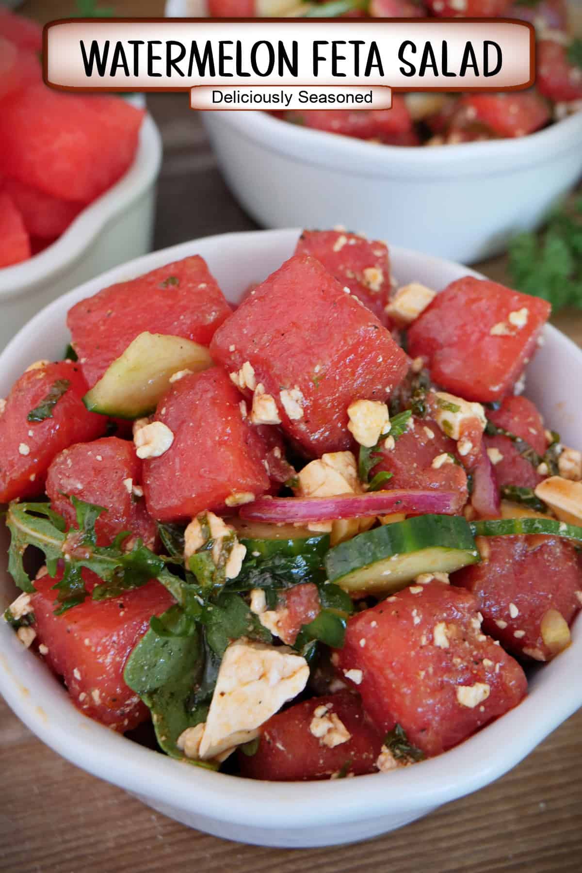 A white bowl with a serving of watermelon feta salad in it, and a title overlay at the top.