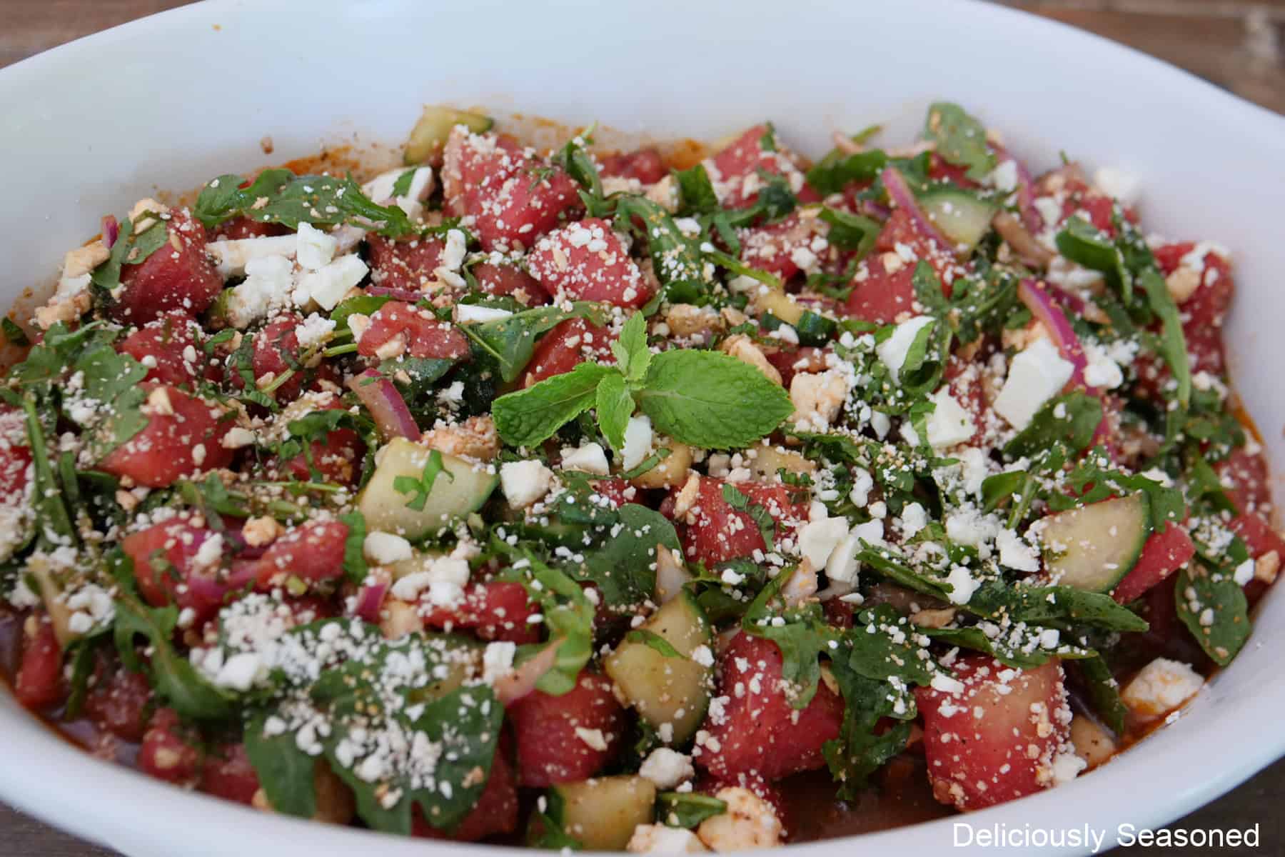 An oval what baking dish filled with watermelon feta salad.