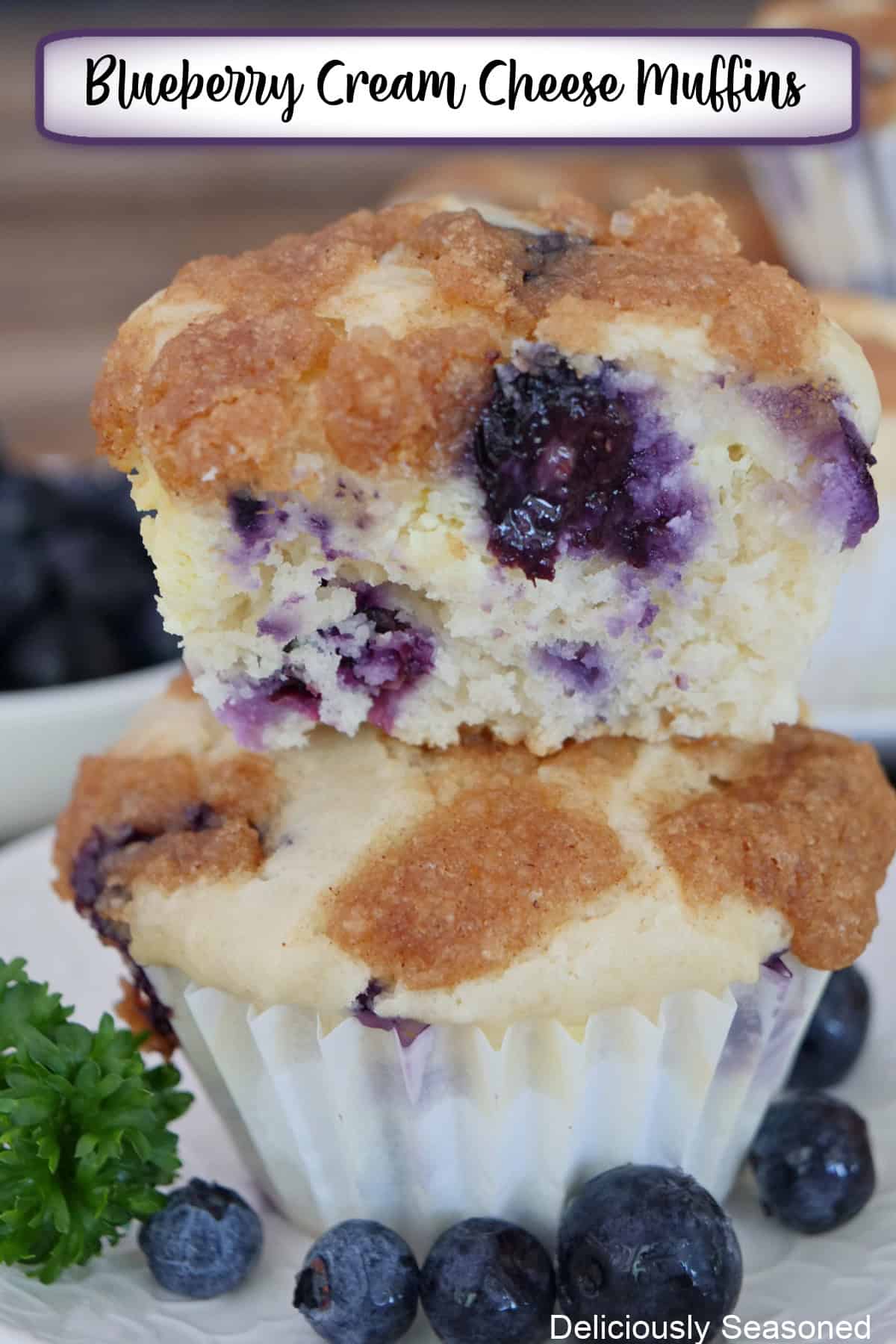 Two blueberry cream cheese muffins stacked on top of each other with a bite out of the top muffin, and a title overlay at the top.