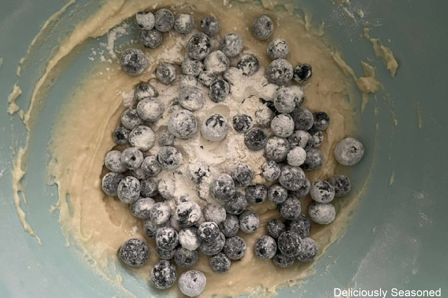 Blueberry muffin batter with blueberries added to the batter.