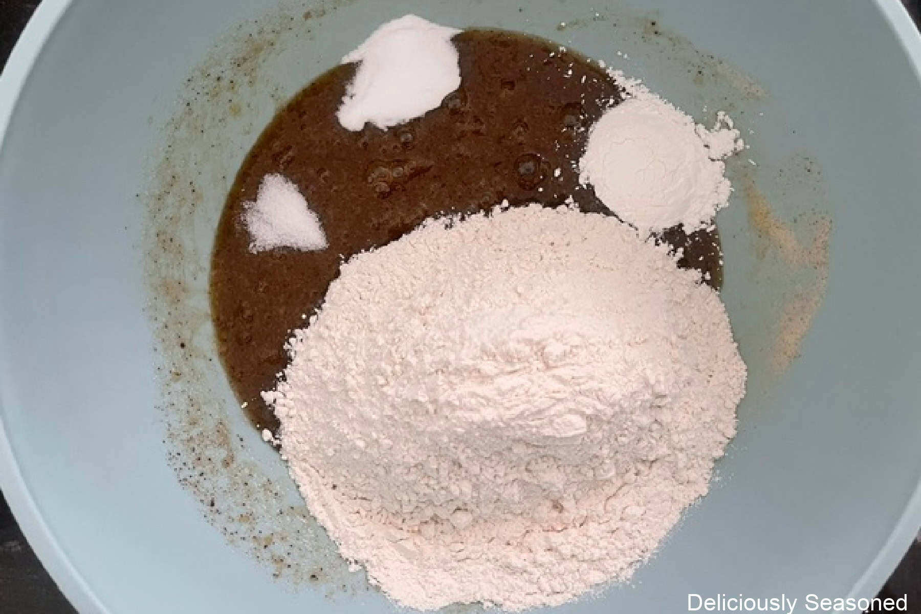 A mixing bowl with the browned butter, dry ingredients and wet ingredients in it.