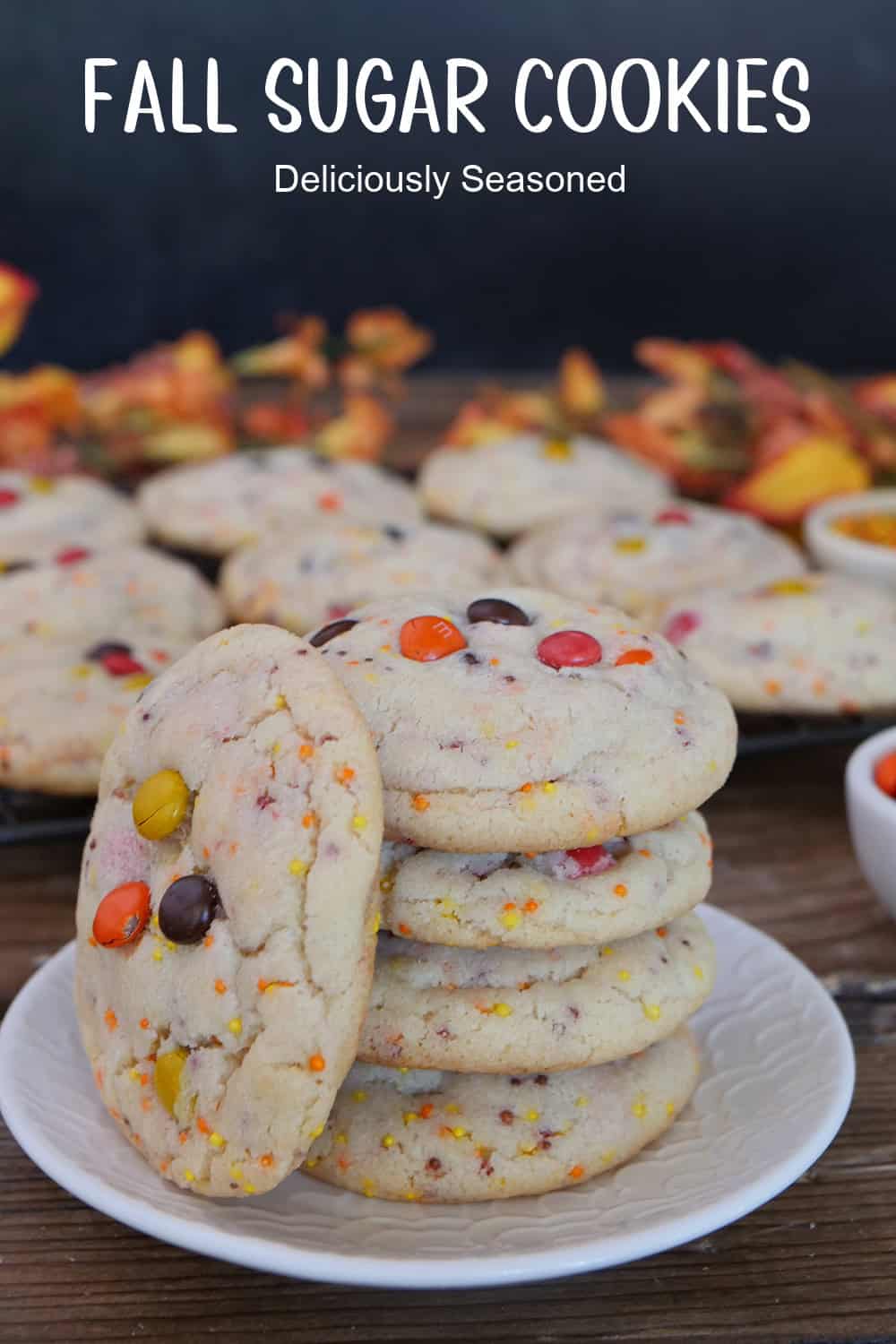 A white plate with blue trim with a stack of 5 fall sugar cookies on it with fall decorations in the background, and a title overlay at the top.