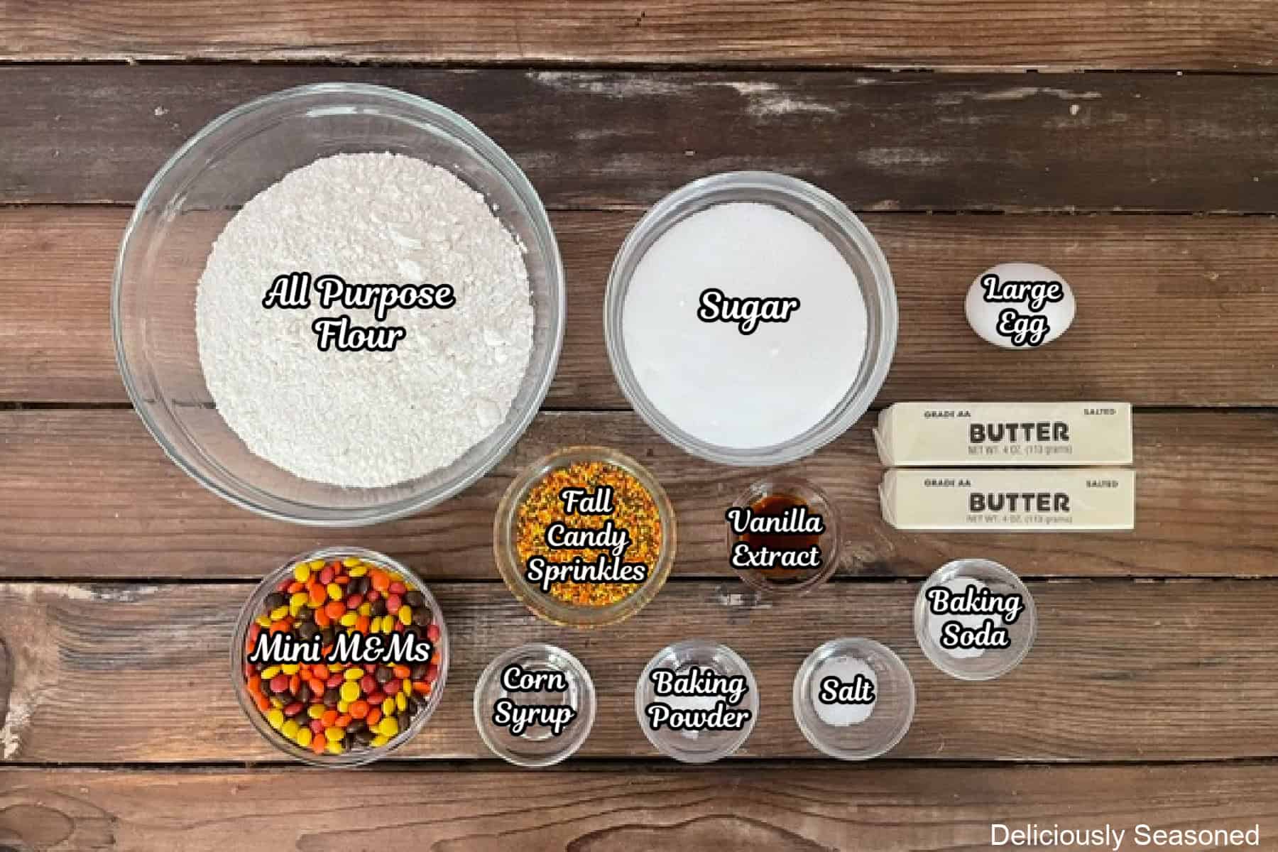 A wood surface with all the ingredients placed on it to make fall sugar cookies.