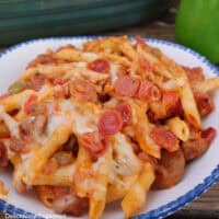 A blue trimmed white bowl with a serving of pepperoni sausage pizza pasta in it.