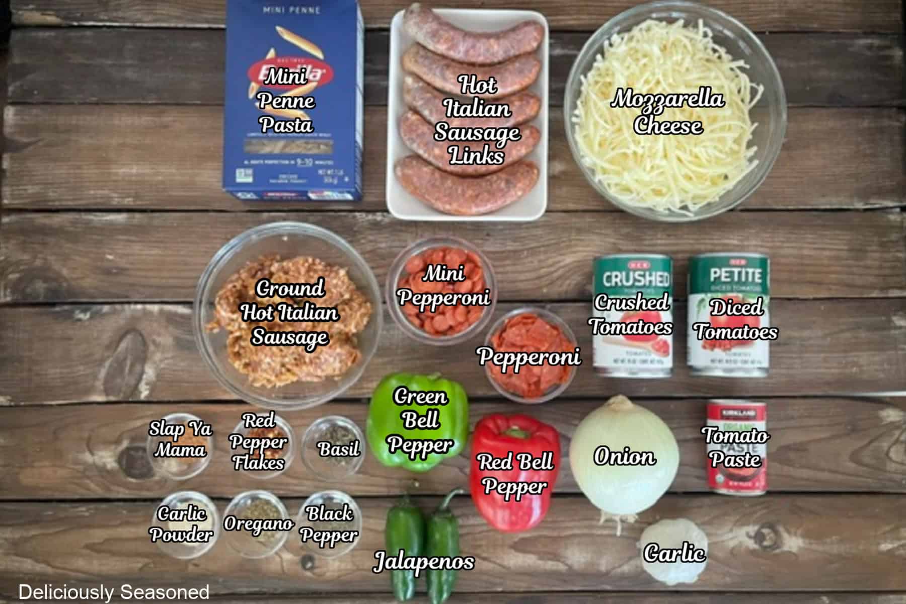 A rustic wood surface with all the ingredients placed on it to make pepperoni sausage pizza pasta.