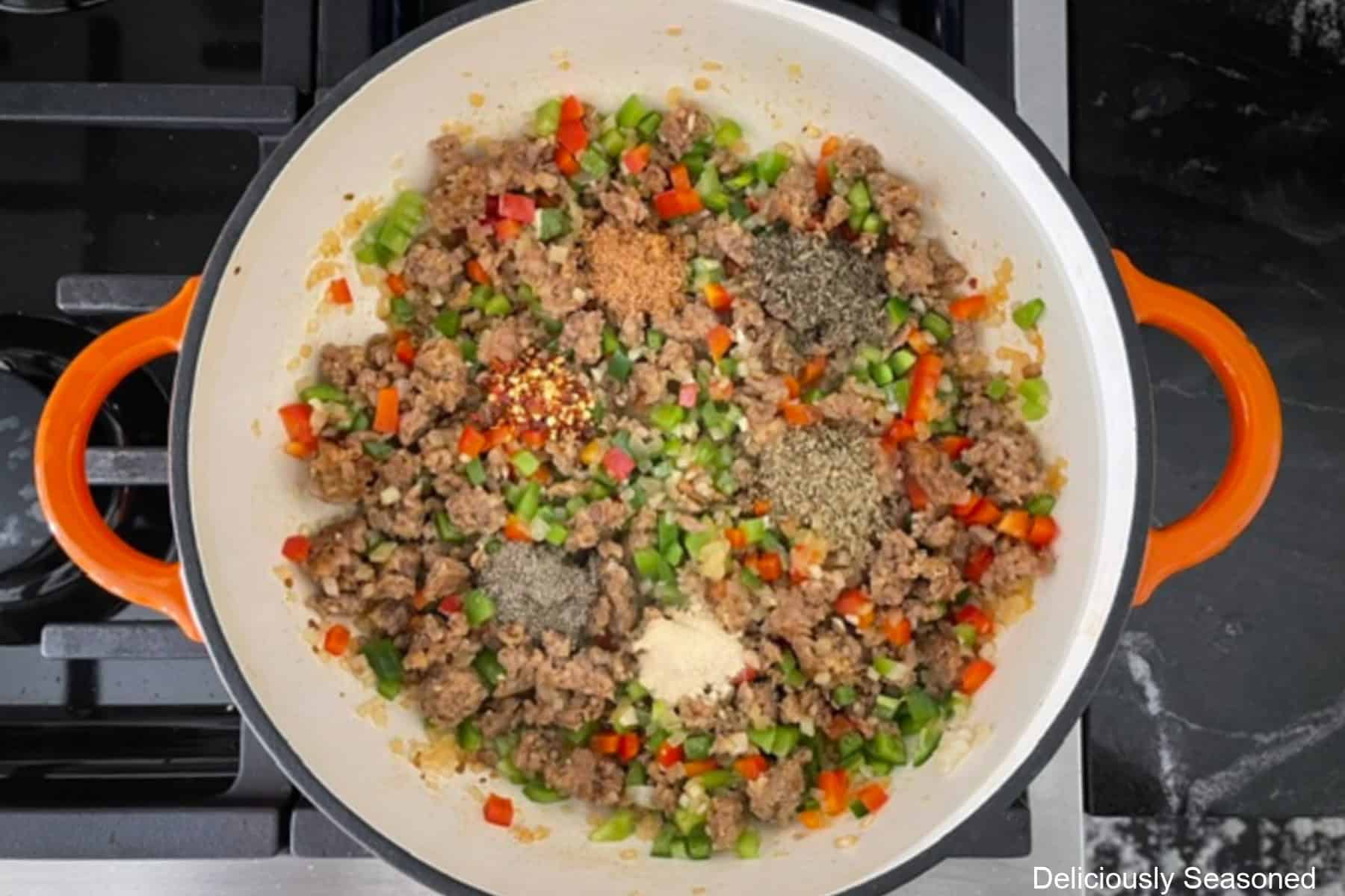 A frying pan with Italian sausage and onions, veggies, and seasonings added.