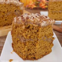 A slice of pumpkin spice coffee cake on a white plate with a bite taken out of it.