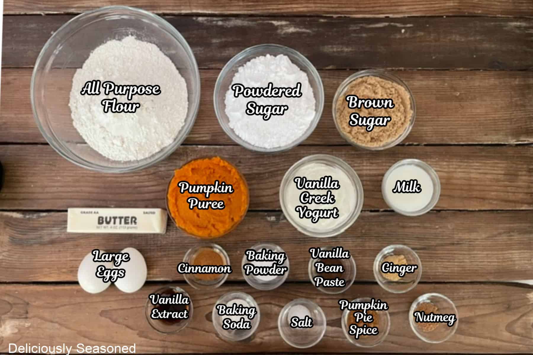 A rustic wood surface with all the ingredients placed on it to make pumpkin spice coffee cake.