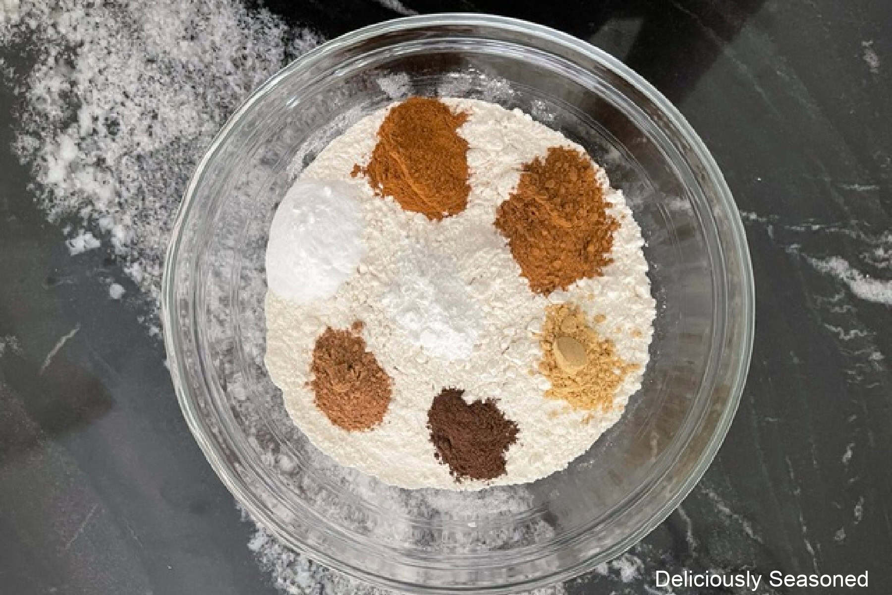 A glass bowl with the dry ingredients in it for pumpkin spice coffee cake.
