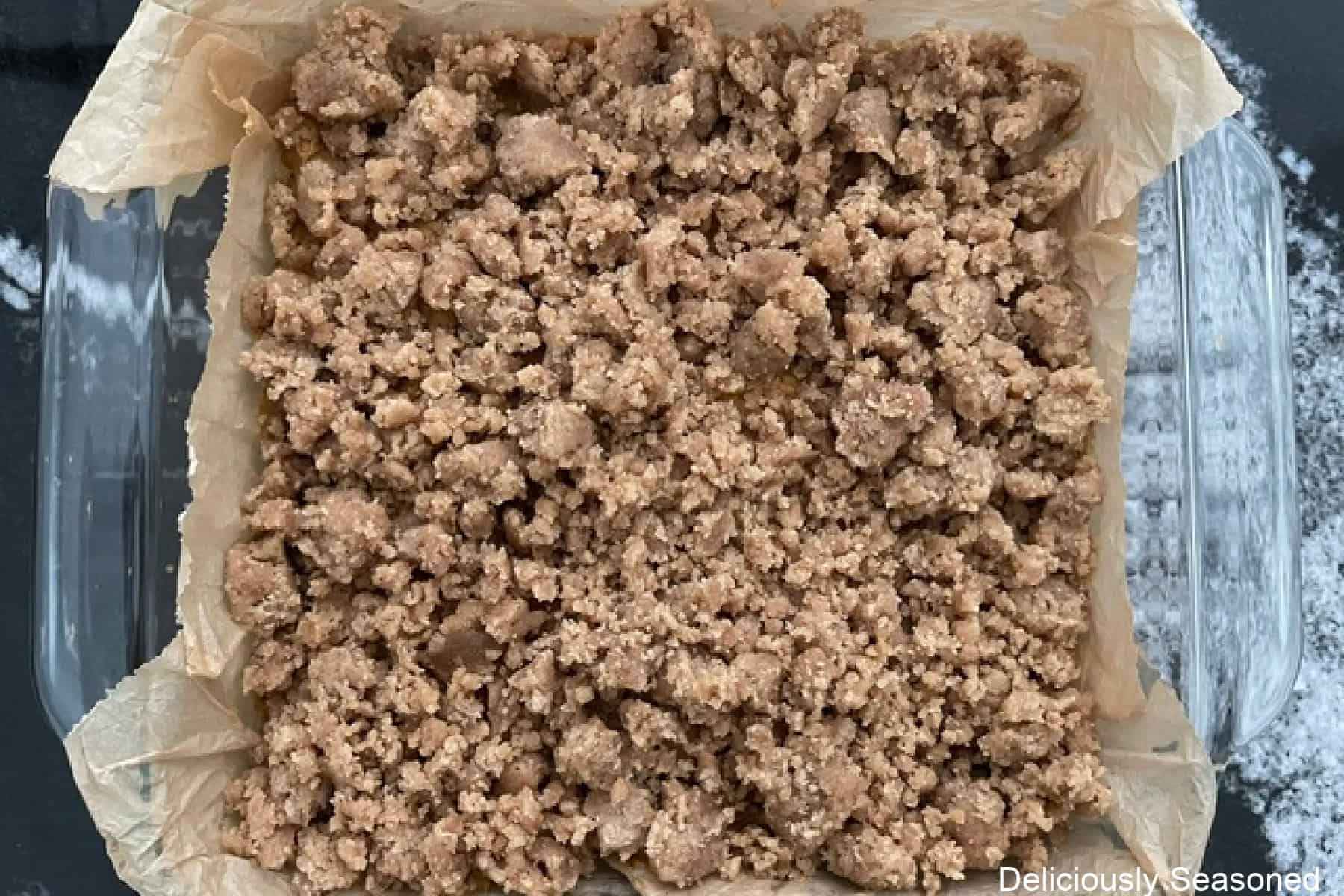 An 8 by 8 baking dish with a pumpkin spice coffee cake in it before going in the oven.