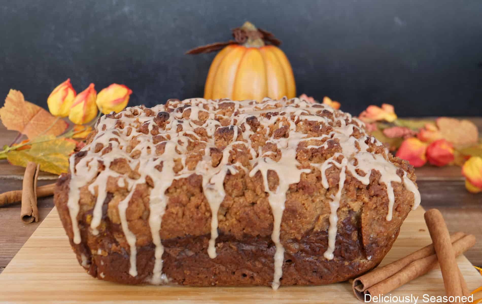 A wood surface with a pumpkin spice coffee cake on it before being sliced into serving pieces..