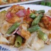 A white plate with blue trim filled with a serving of sheet pan chicken cordon bleu with stuffing.