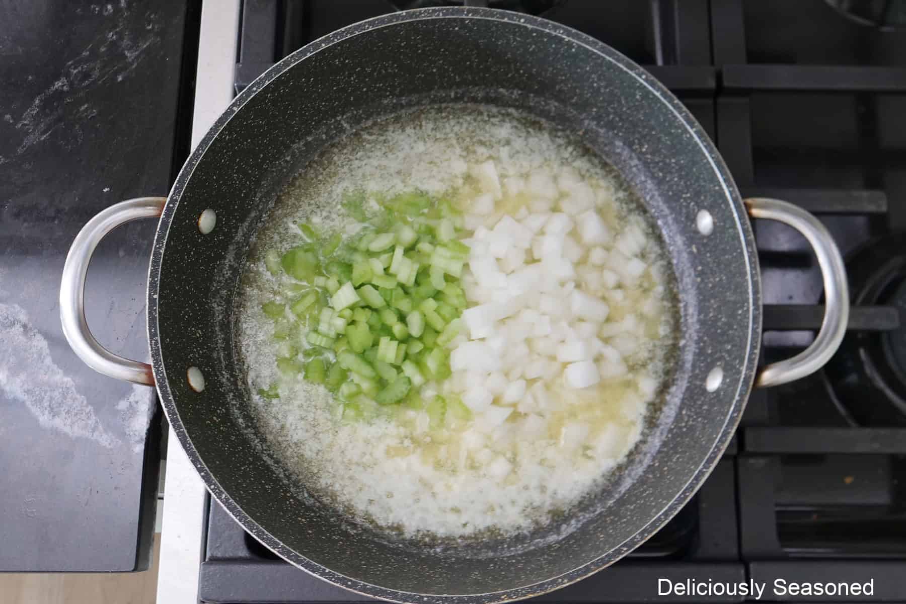 A frying pan with butter, onions, and celery cooking in it.
