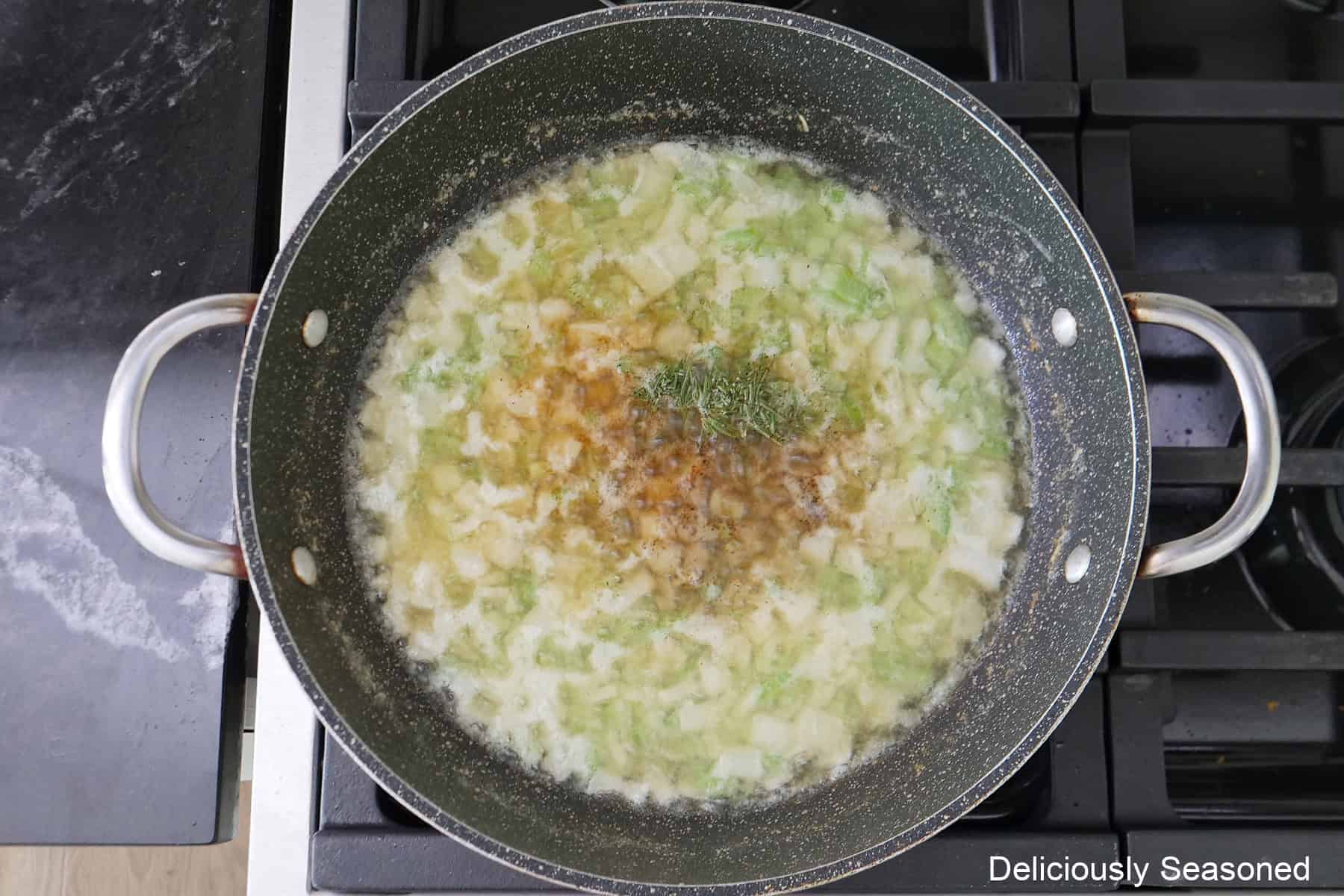 A frying pan with tender onions, celery, butter, and seasonings in it.
