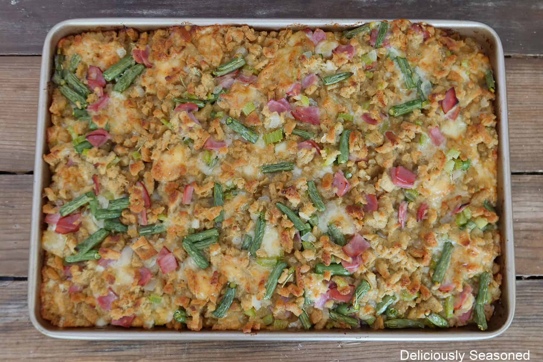 A wood surface with a baking sheet filled with a baked sheet pan chicken cordon bleu on it.