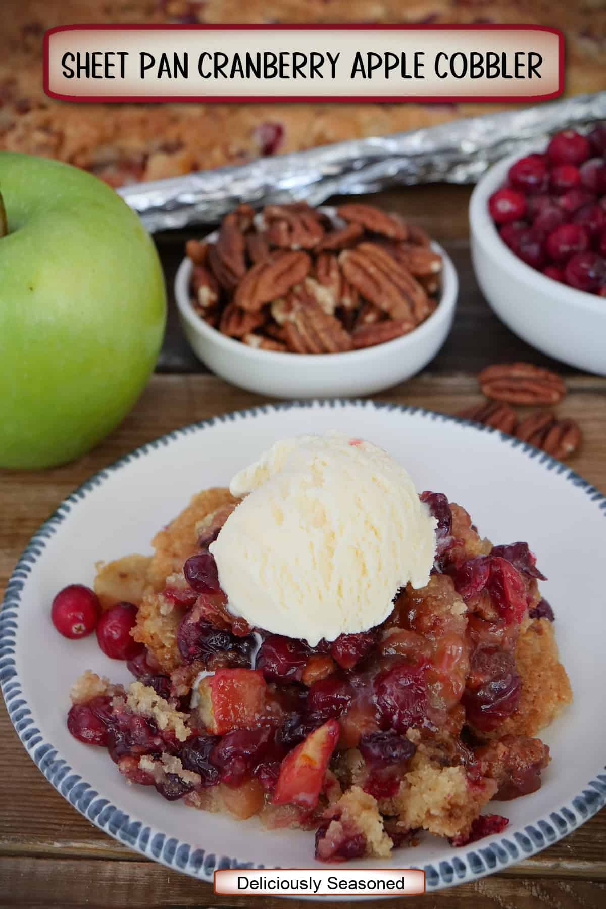 A white plate with blue trim with a serving of sheet pan cranberry apple cobbler with a scoop of vanilla ice cream on top, and a title overlay at the top.