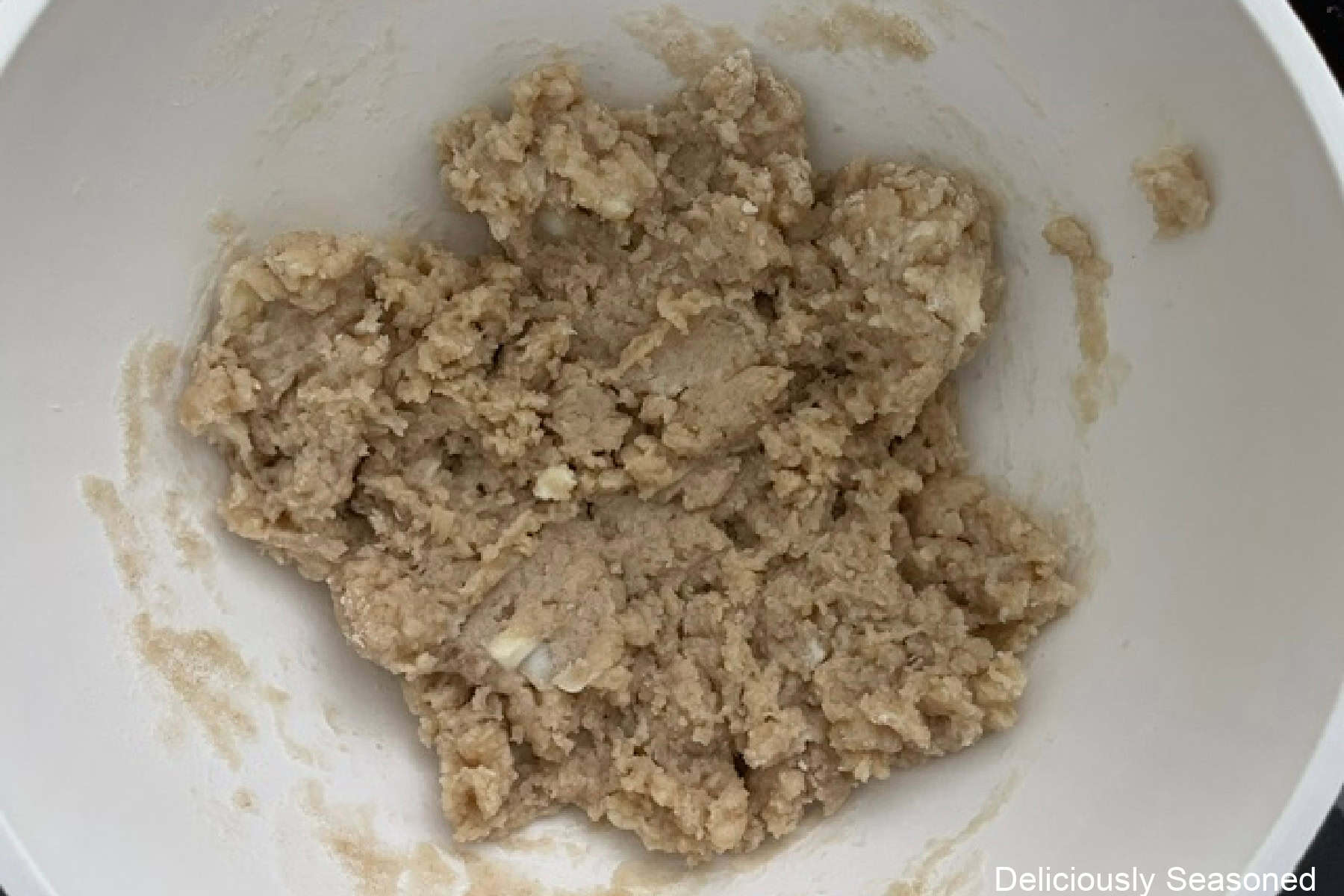 A white bowl with the cobbler topping mixed together in it.