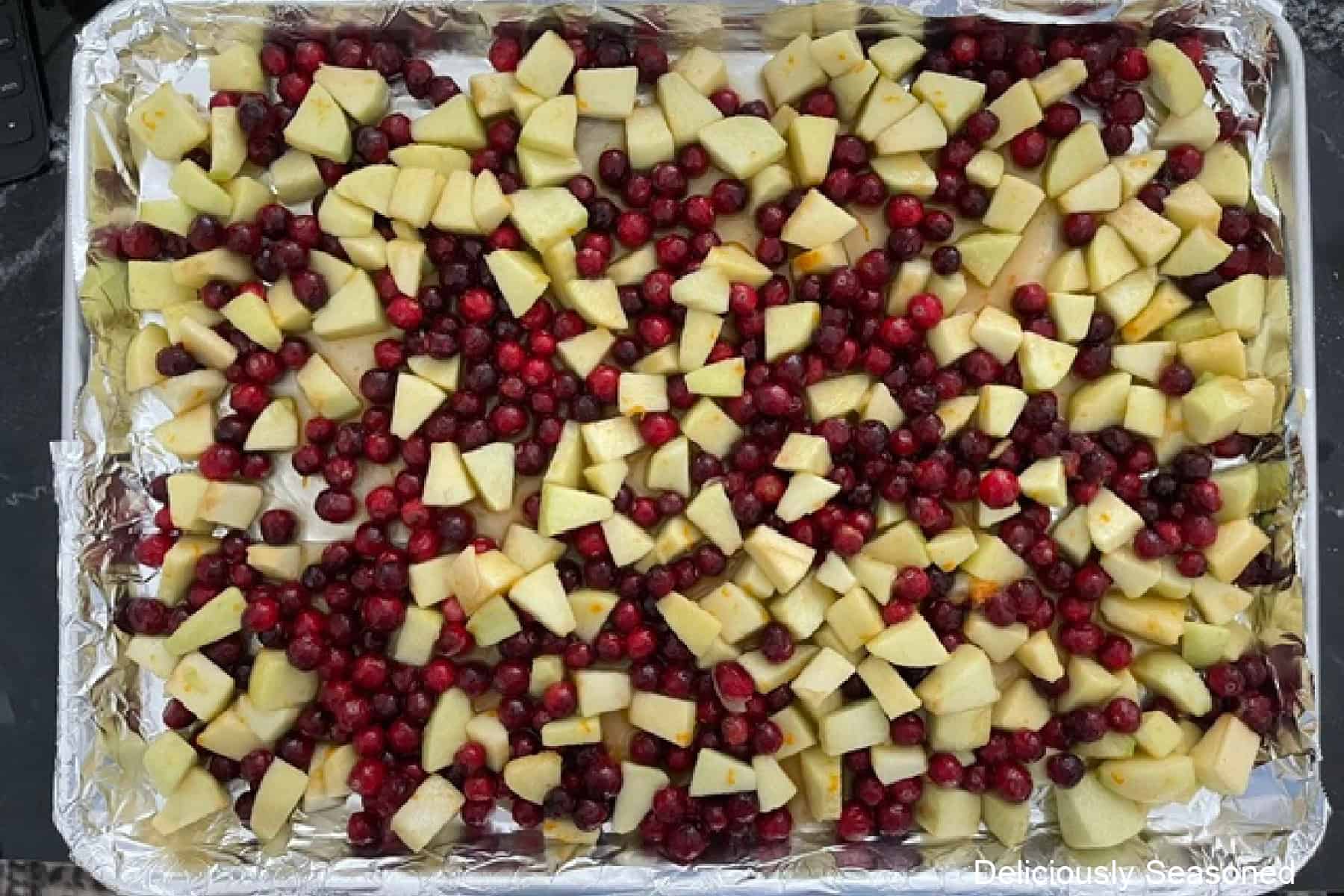 A foil lined baking sheet with cranberry apple filling spread out in an even layer.