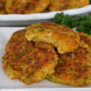 A white plate with a stack of sweet potato broccoli cheddar fritters on it with a bite taken out of the fritter on top.