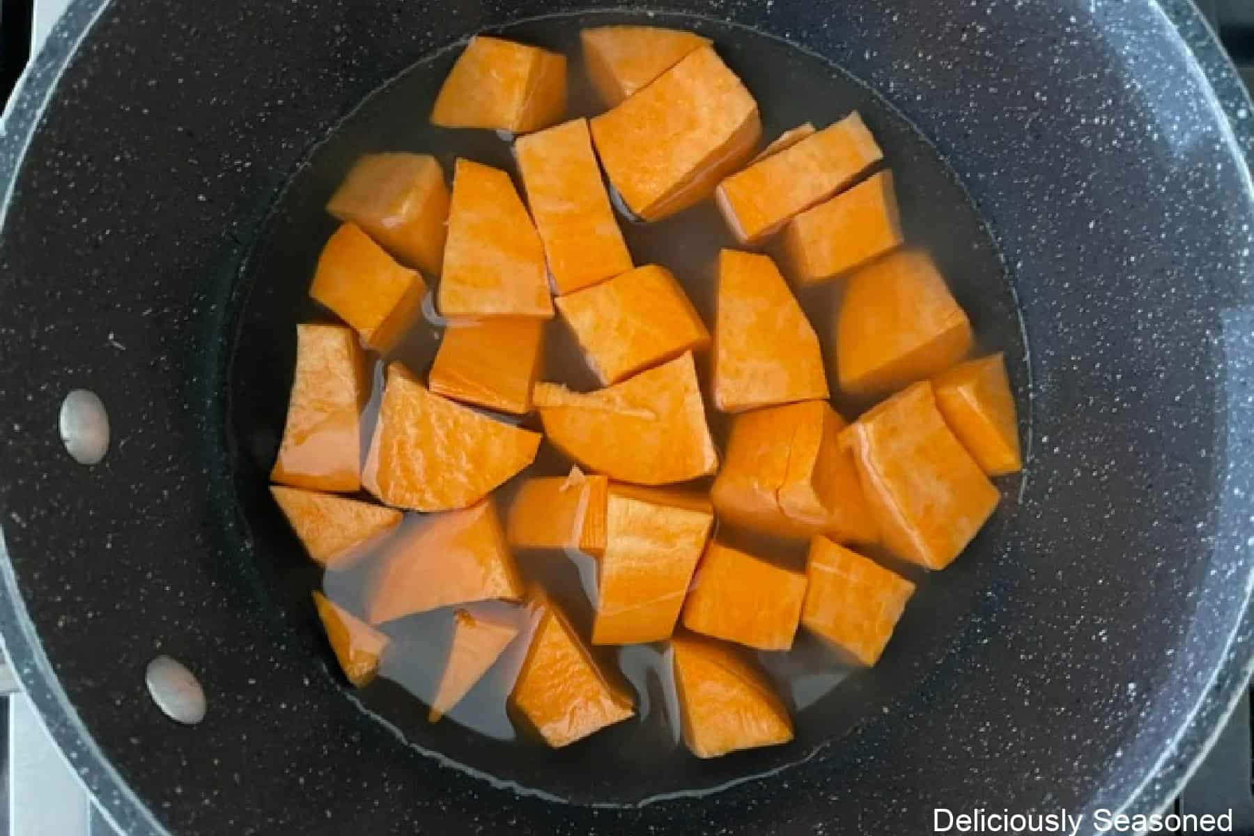 A saucepan with cubed sweet potatoes in it.