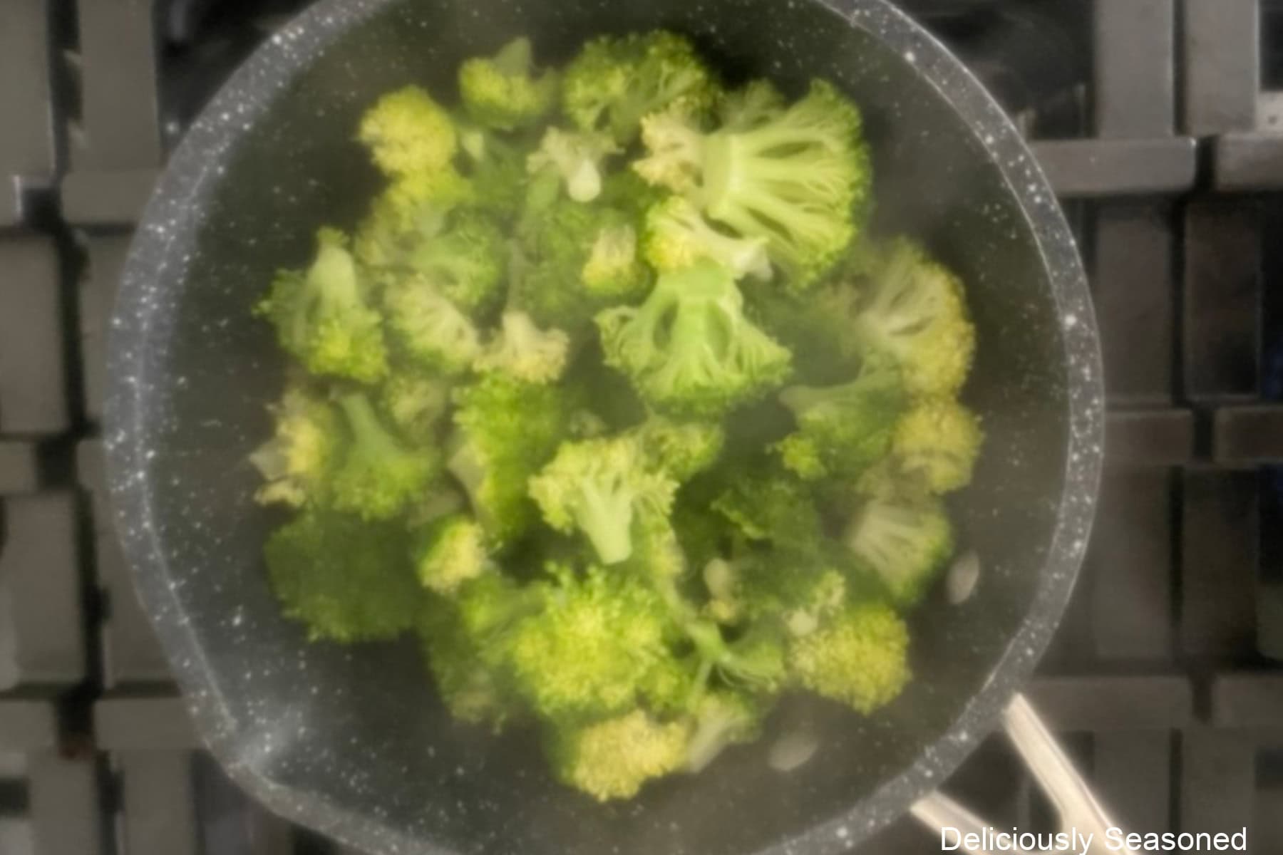 A saucepan with broccoli florets steaming.